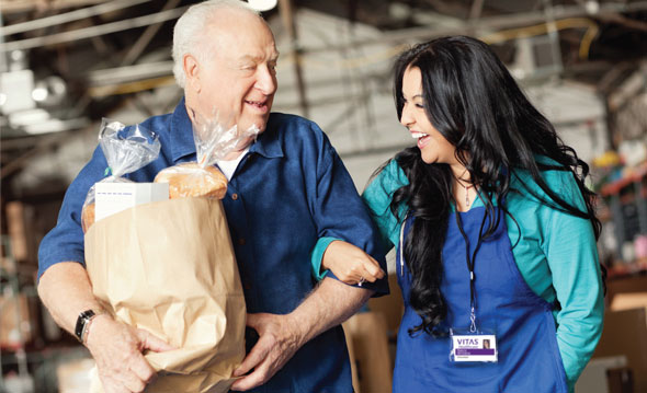 A woman helping a man with a bag of groceries